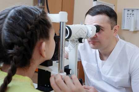 产科儿医生在诊所用割眼灯检查一名十几岁女孩的眼部图片