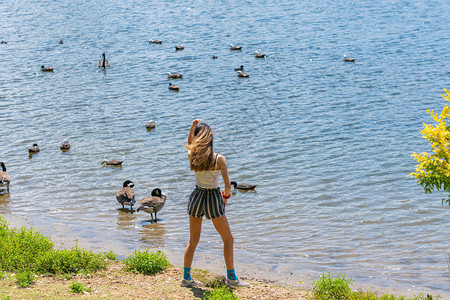 年轻女子站立在水边的湖边行进有图片