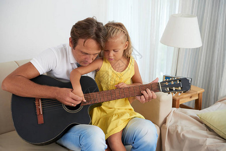 年轻男人教女儿弹吉他图片