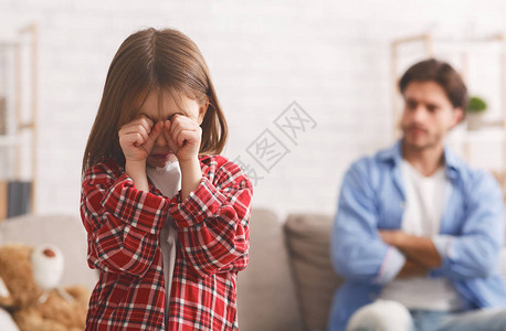 小女孩哭泣愤怒的男子坐在沙图片