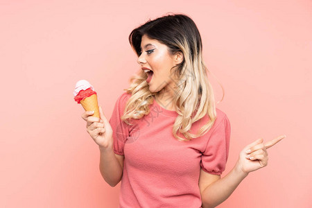 年轻女孩拿着一个玉米饼冰淇淋与粉红背景隔绝面部图片