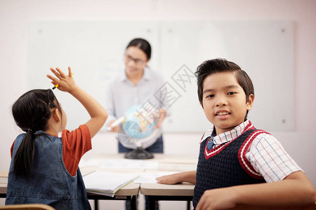 坐在椅子上看摄影机的亚洲男学生肖像图片