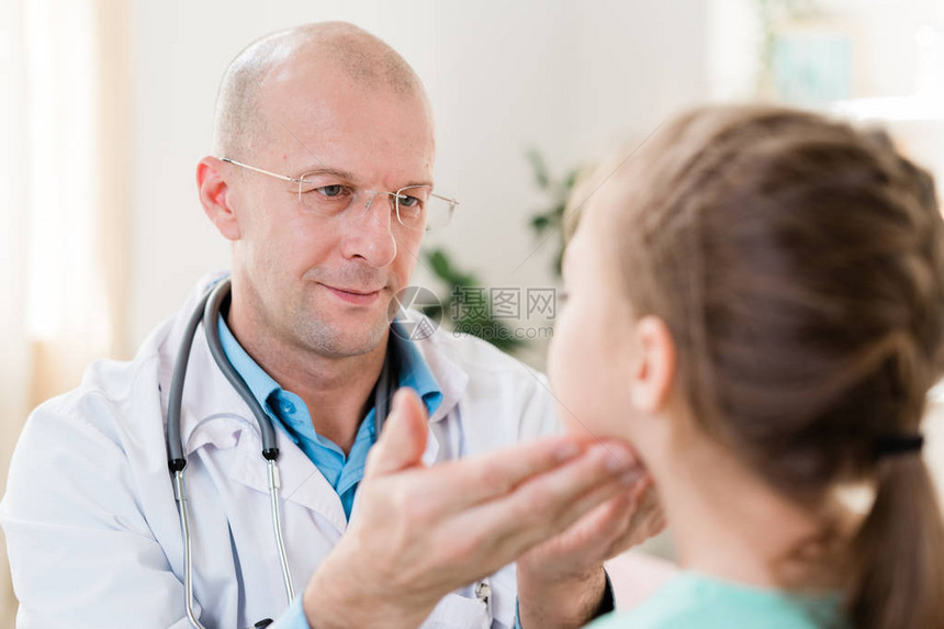 眼镜和白衣中的小儿科医生在用手指检查她的腺时图片
