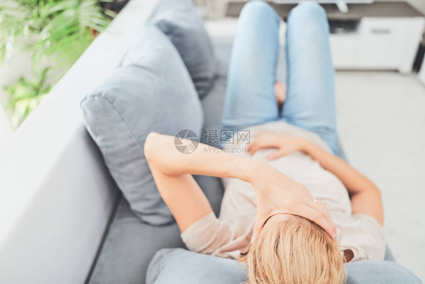 躺在沙发上时有胃病问题的女人图片