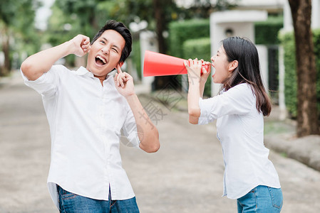 亚洲女人在户外用扩音器对亚洲男人大喊叫图片