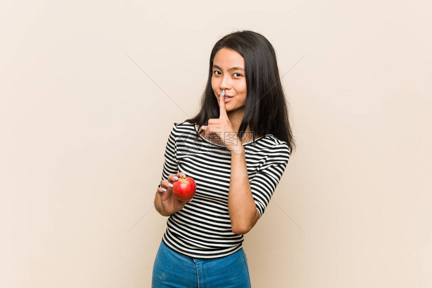 年轻的亚洲女人拿着苹果保守秘密或要求保持沉默图片