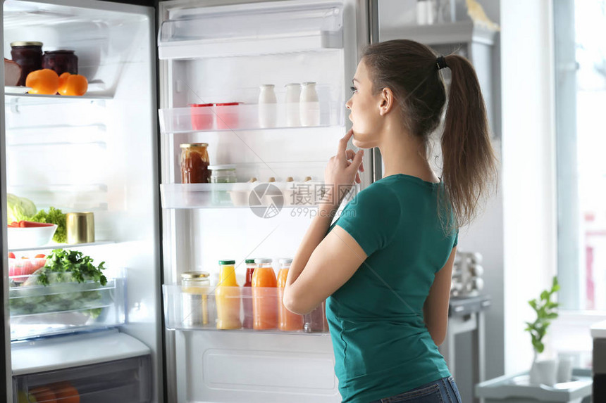 站在家里打开冰箱附近的女人图片