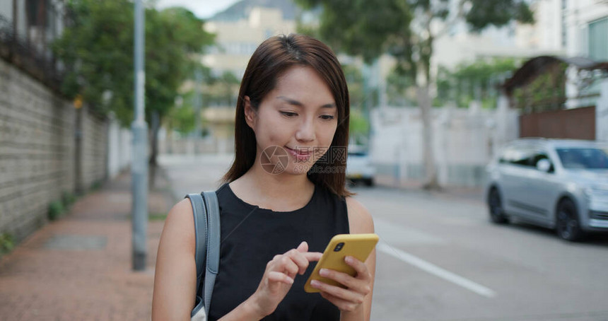 女人用手机走在街上图片