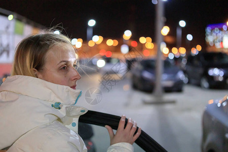 年轻女孩晚上在停车场下车的图片