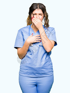 身穿医疗制服的年轻成年医生女人闻到某种臭味和恶心难以忍受的气味图片