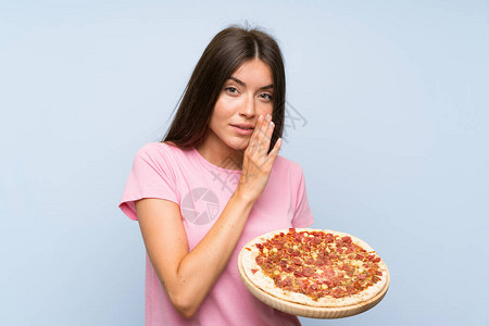 年轻漂亮女孩拿着披萨在隔绝的蓝图片