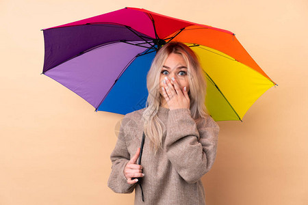 年轻女孩拿着雨伞在孤立的背景和面部表情上图片
