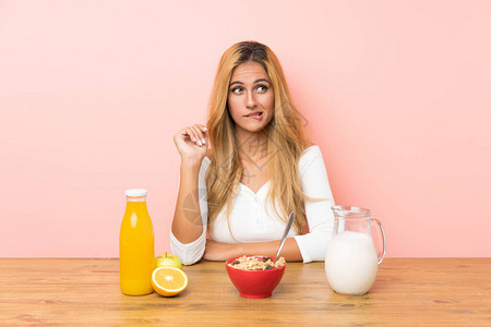 年轻金发女子吃早餐牛奶时有怀疑和图片