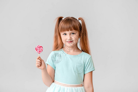 浅色背景中带棒糖的可爱小女孩图片