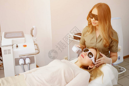 美容诊所工作人员使用改进的特殊装置阳光对女病人面部图片