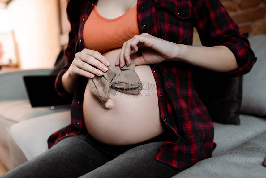 孕妇在肚子附近养着婴儿袜图片