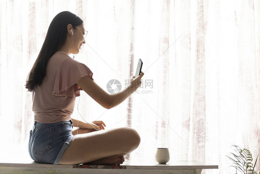 坐在窗户旁边的长凳上年轻妇女图片
