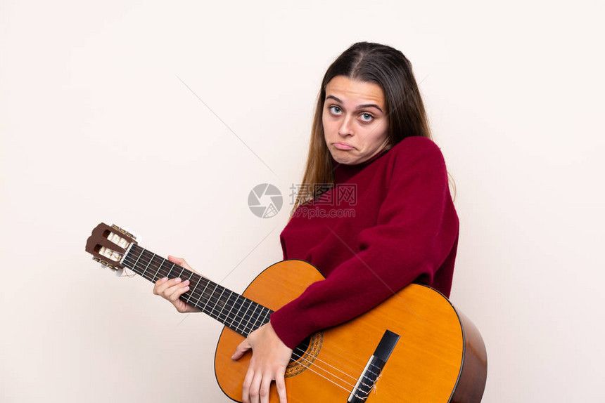 带着吉他的女孩在与世隔绝的背景上举起肩膀时图片