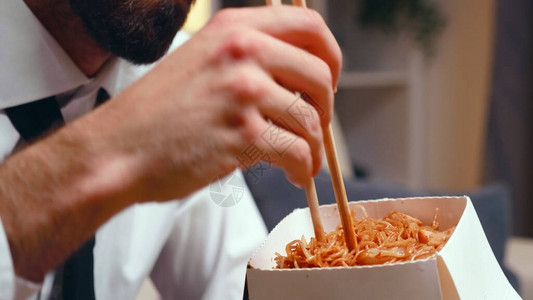 疲倦的企业家在吃面条和筷子图片
