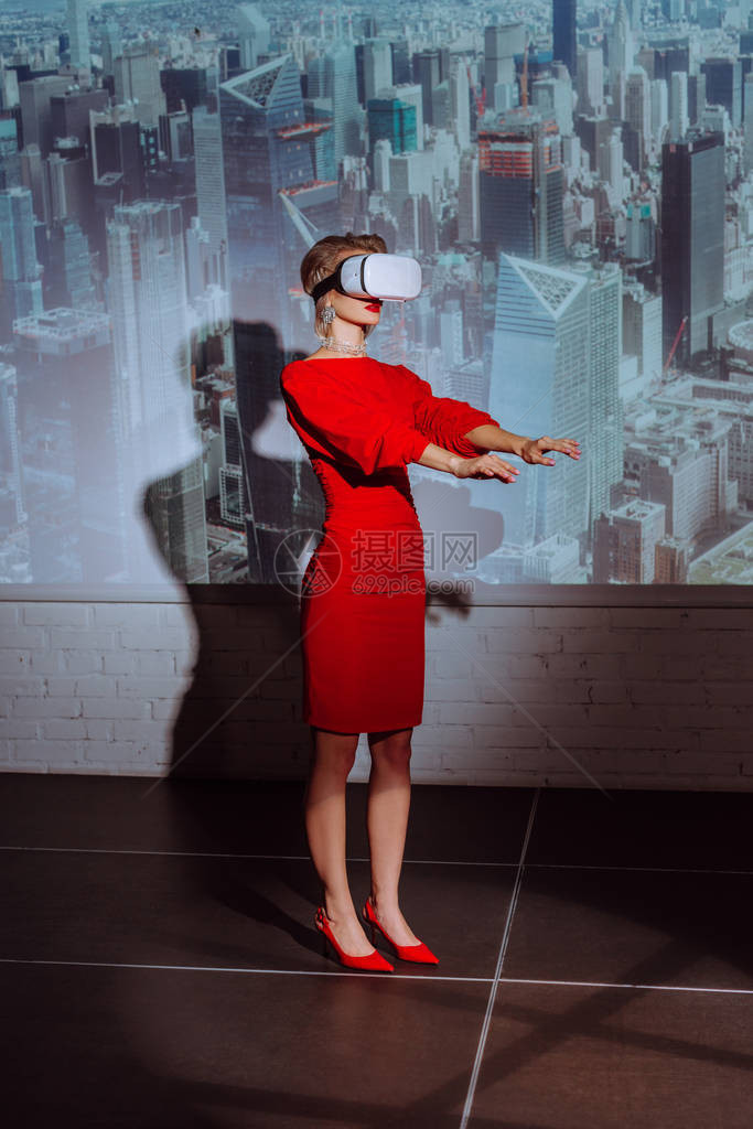 穿着红裙子和城市背景虚拟现实头巾的时髦女图片
