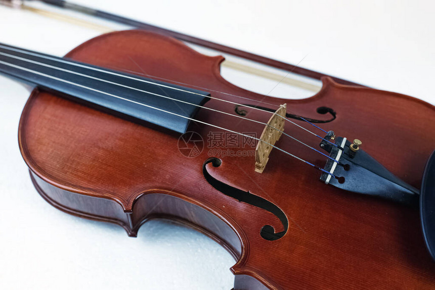 木小提琴放在白色背景在模糊的弓前展示图片