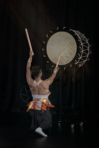Taiko鼓手在舞台上用黑色背景击图片