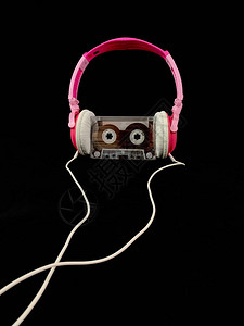 塑料盒式磁带和音频耳机黑色背景上的音乐盒式磁带概念图片