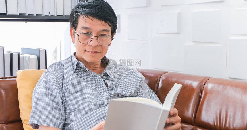 亚裔老人在家中看沙发的书图片
