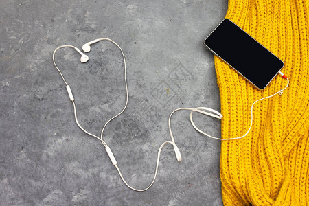工作台的创意平躺照片用耳机和手机在芥末冬羊毛围图片