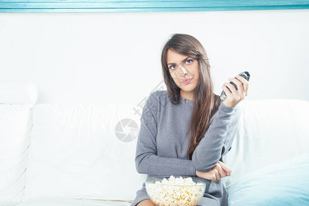 一个年轻女子在家看电视时吃图片