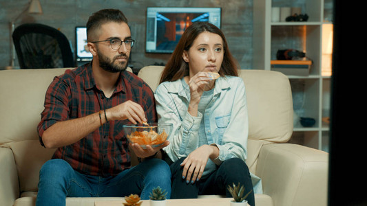 专注的caucasian年轻夫妇一边看电视图片