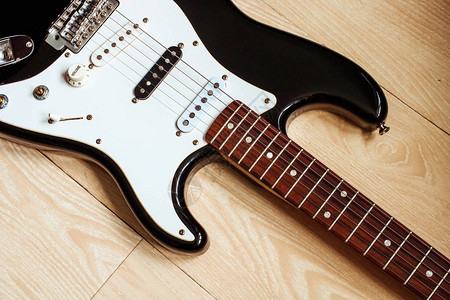 黑白电吉他电吉他主体的顶视图靠在木地板上音乐设备乐器图片