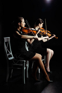 专业青年音乐家在黑暗舞台的小提琴上背景图片