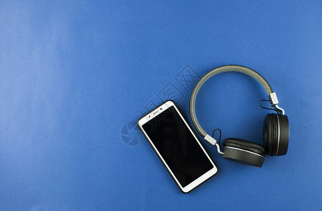蓝色背景上的耳机和智能手机顶部视图带复制空间的耳图片