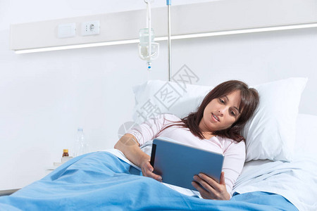 年轻的微笑病人躺在医院的床上图片