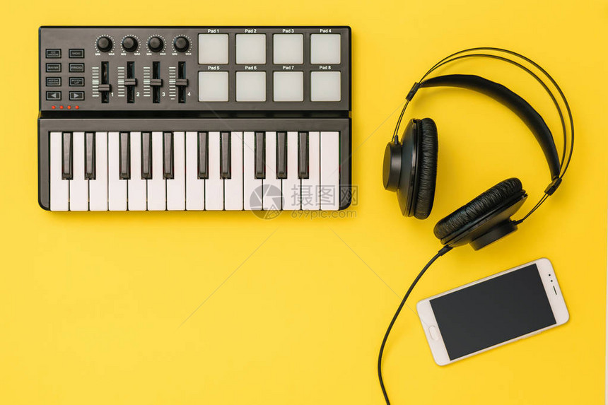 明亮的黄色背景上的智能手机音乐混音器和耳机工作场所组织的概念用于录音交流和图片