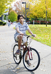 双种族少年男孩户外骑自行车在阳光明日的公图片