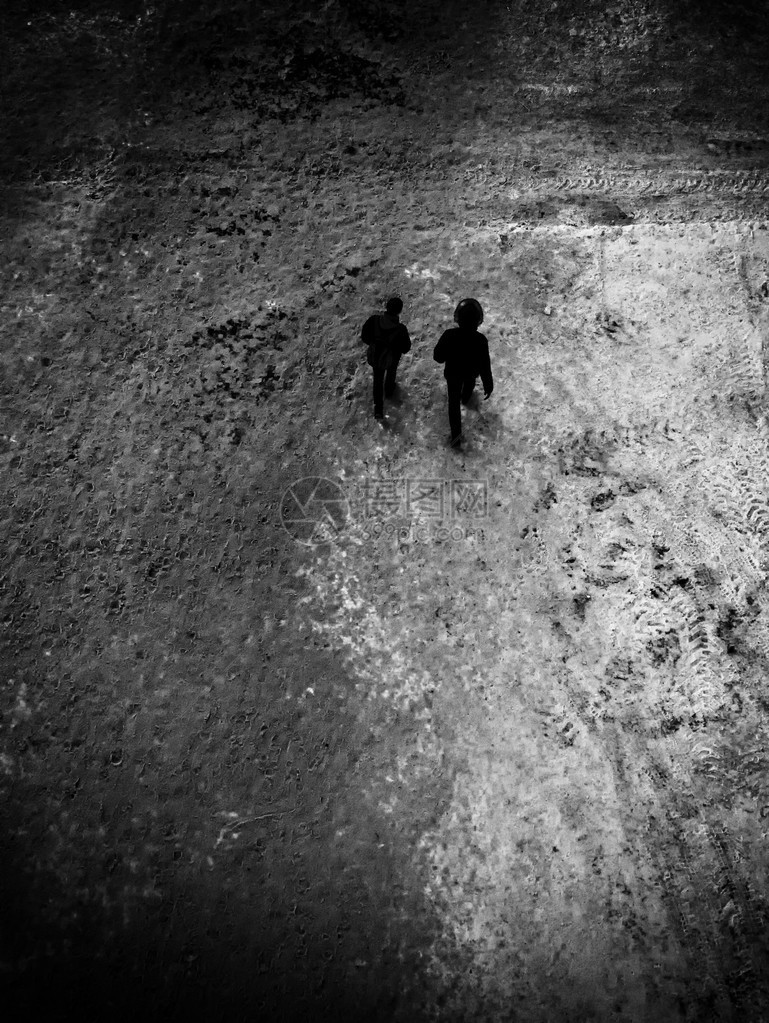 两个青少年在冬天沿着雪覆盖的小路行走图片