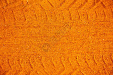 沙子上的橙色车胎轨迹从沙子背景图片