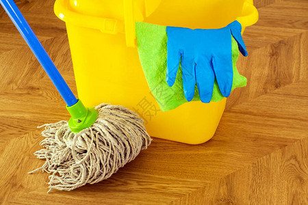 地板清洁拖把和黄色桶上的蓝色手套图片