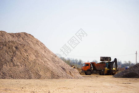 拖拉机正在将沙子装入建筑工地的卡车厢在前景一座沙图片