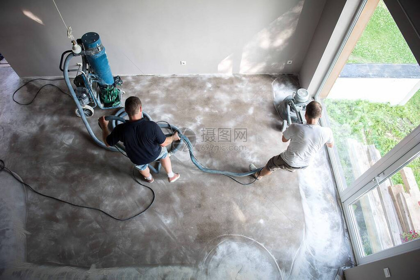 客厅的建筑工人在应用环氧树脂地板之前研磨混凝土表面聚氨酯和环氧树脂地板图片