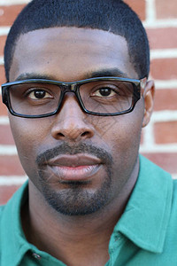戴眼镜的年轻黑人男子的特写镜头在砖墙背图片
