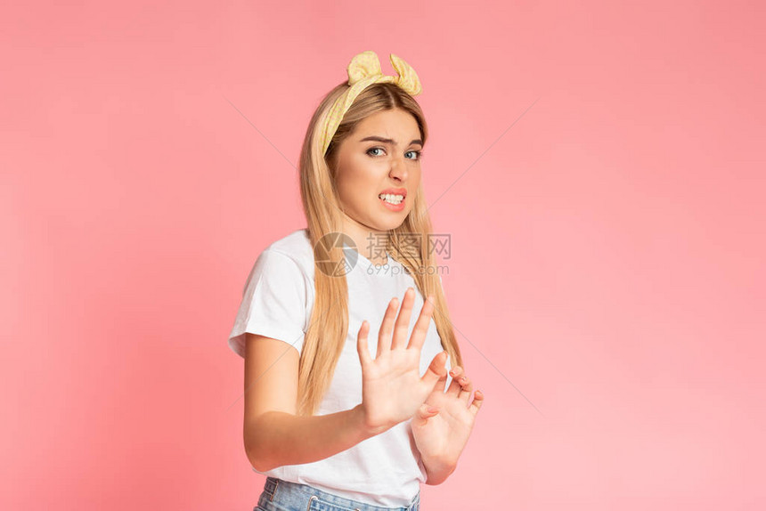 讨厌的金发女孩面部表情令人作呕站在粉红色工作室图片