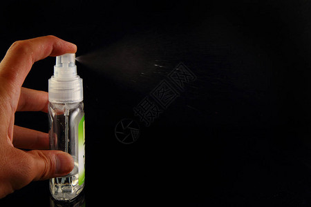 一个人的手在黑色背景上喷洒呼吸清新剂图片