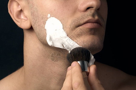 男人用剃须刷来涂刮发泡沫图片