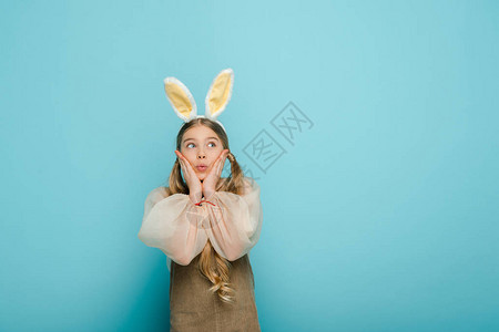 惊喜的小孩兔子耳朵触摸着脸部看图片