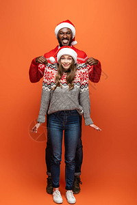 快乐的非洲男人美国男人举起女朋友在圣诞节毛衣图片