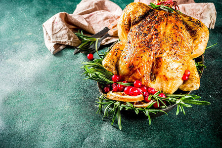 传统的圣诞节和感恩节烤全鸡配水果和迷迭香深绿色混凝土桌面图片