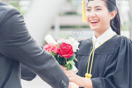 毕业的女人概念年轻的微笑女人在完成教育后得到了花研究生图片